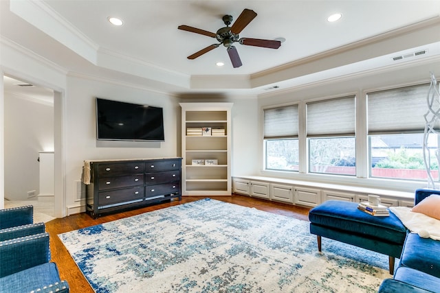 living room with dark hardwood / wood-style floors, ornamental molding, a raised ceiling, and ceiling fan