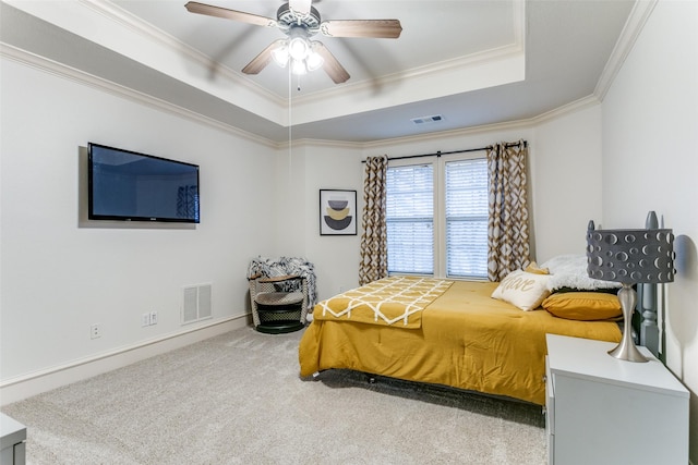 carpeted bedroom featuring a tray ceiling, ornamental molding, and ceiling fan