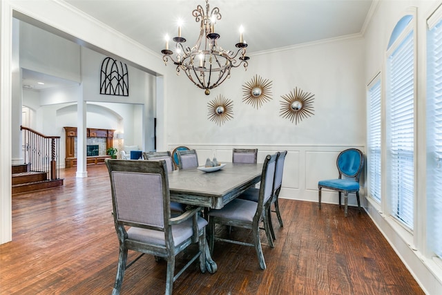 dining area with ornamental molding, a stone fireplace, a healthy amount of sunlight, and dark hardwood / wood-style flooring