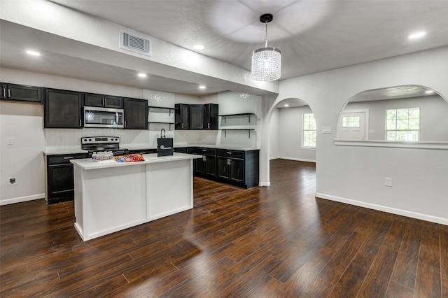 kitchen with a center island, hanging light fixtures, tasteful backsplash, a chandelier, and appliances with stainless steel finishes