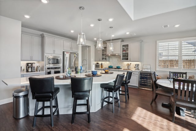 kitchen with appliances with stainless steel finishes, a large island, hanging light fixtures, and dark hardwood / wood-style flooring