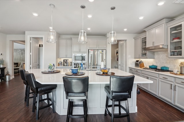 kitchen featuring a spacious island, dark hardwood / wood-style flooring, stainless steel appliances, and hanging light fixtures