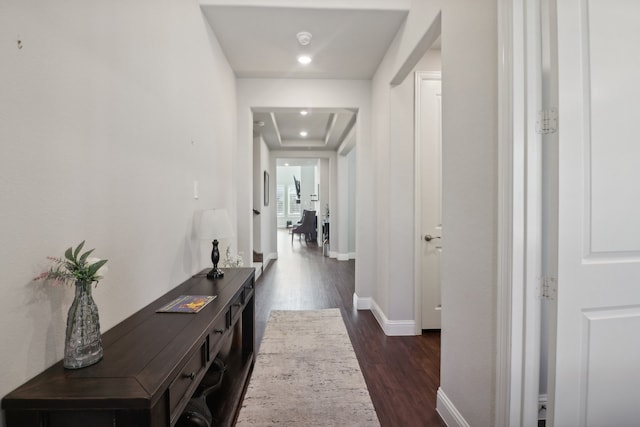 corridor featuring a raised ceiling and dark hardwood / wood-style floors