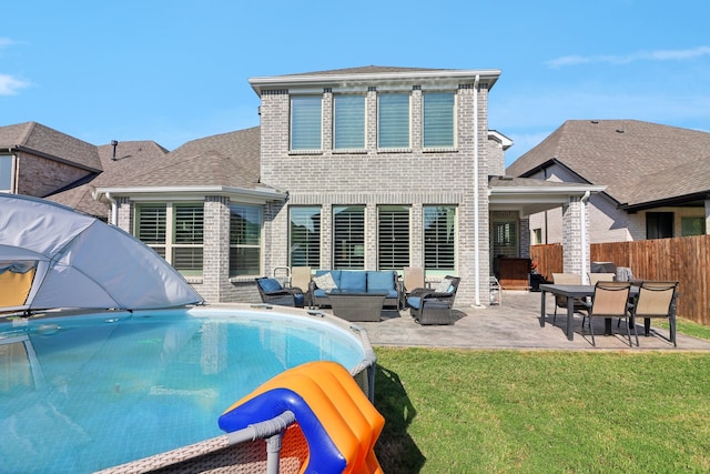 back of property featuring outdoor lounge area, a lawn, a fenced in pool, and a patio