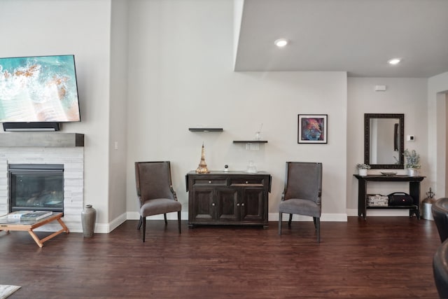 living area with a tiled fireplace and dark hardwood / wood-style floors