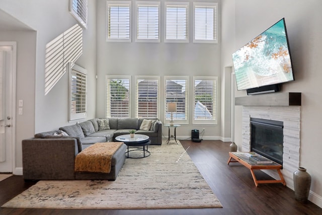 living room with a high ceiling, dark hardwood / wood-style flooring, and a fireplace