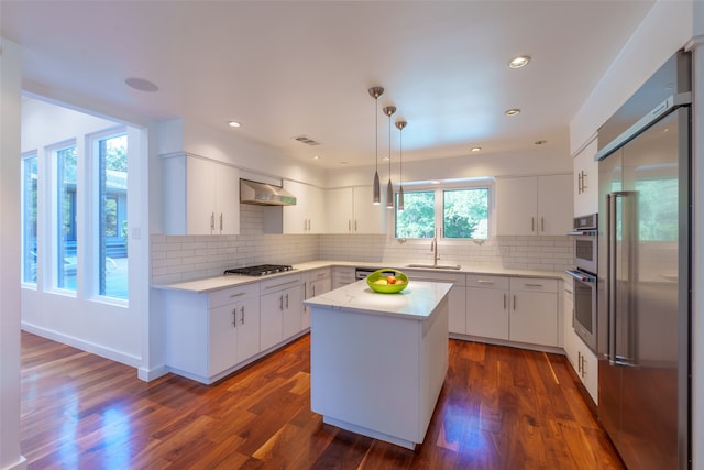 kitchen featuring sink, hanging light fixtures, stainless steel appliances, a kitchen island, and white cabinets