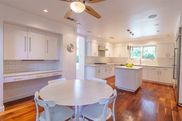 kitchen with pendant lighting, decorative backsplash, a center island, and dark wood-type flooring