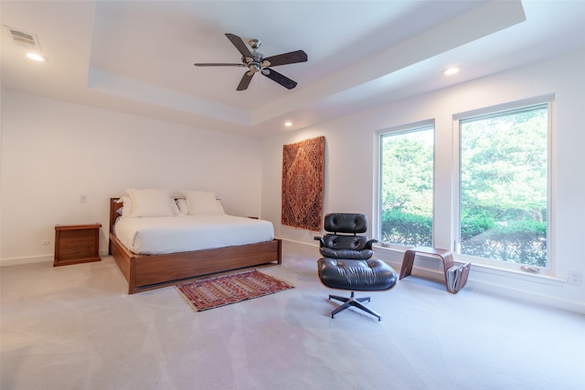 bedroom featuring light carpet, a tray ceiling, and ceiling fan