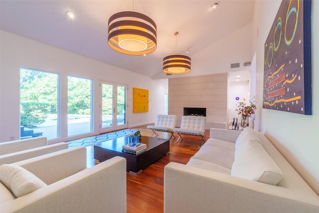 living room with hardwood / wood-style flooring, a large fireplace, and high vaulted ceiling