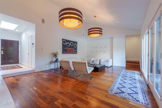 interior space featuring a skylight, hardwood / wood-style floors, high vaulted ceiling, and plenty of natural light