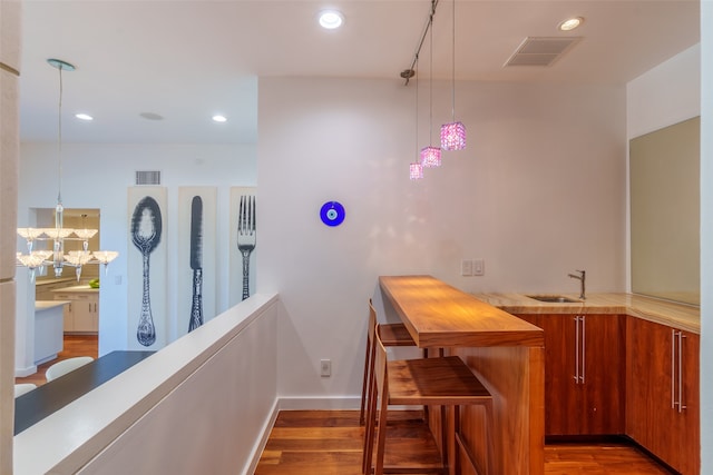 bar with hardwood / wood-style floors, decorative light fixtures, and sink