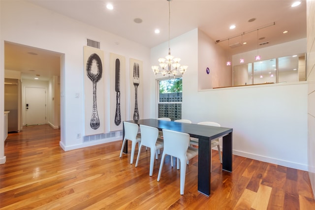 dining space featuring a notable chandelier, track lighting, and light hardwood / wood-style flooring