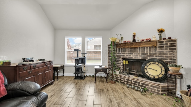 living room featuring a fireplace, vaulted ceiling, and light hardwood / wood-style flooring