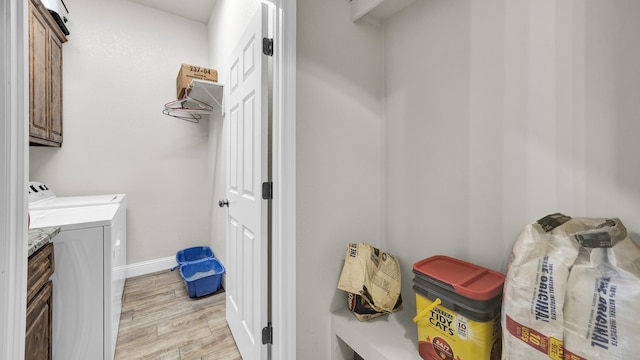 washroom with separate washer and dryer, light hardwood / wood-style flooring, and cabinets