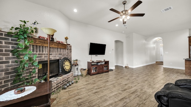 living room with lofted ceiling, light hardwood / wood-style floors, ceiling fan, and a fireplace