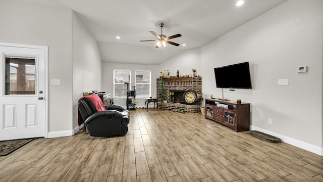 living room featuring light hardwood / wood-style flooring, ceiling fan, vaulted ceiling, and a brick fireplace