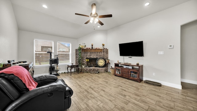 living room featuring light wood-type flooring, vaulted ceiling, a brick fireplace, and ceiling fan