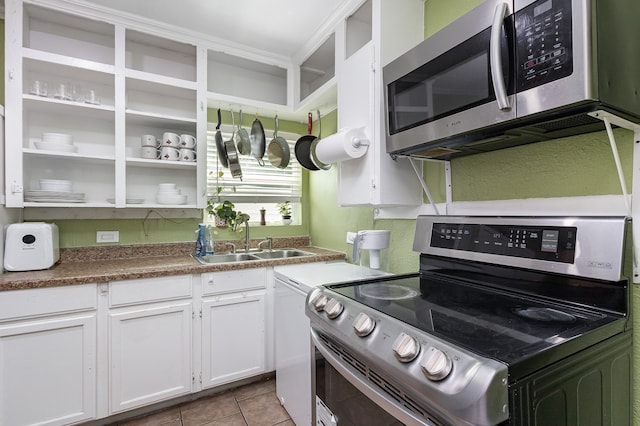 kitchen featuring appliances with stainless steel finishes, light tile patterned floors, white cabinetry, and sink