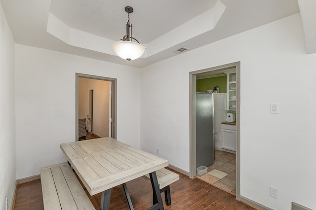 dining room featuring a tray ceiling and dark hardwood / wood-style flooring