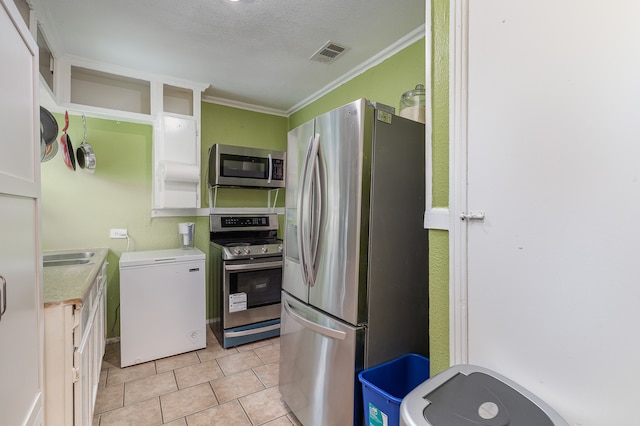 kitchen with a textured ceiling, crown molding, appliances with stainless steel finishes, and white cabinetry