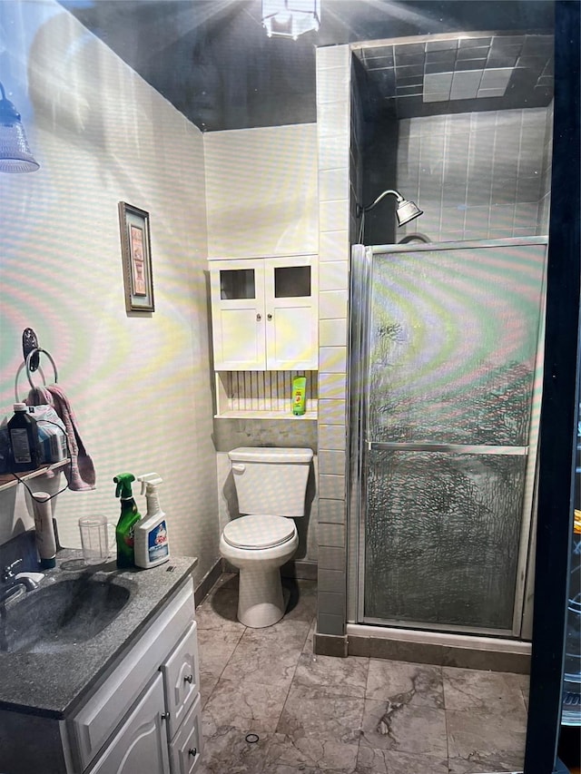 bathroom featuring a shower with door, vanity, and toilet