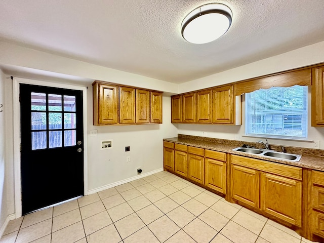 kitchen with light tile patterned floors, a textured ceiling, a healthy amount of sunlight, and sink