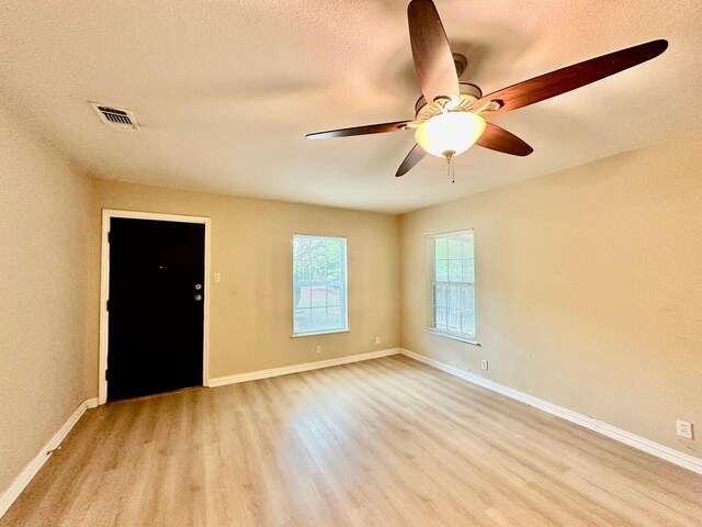 spare room featuring a textured ceiling, light hardwood / wood-style flooring, and ceiling fan