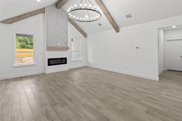 unfurnished living room featuring a notable chandelier, beam ceiling, a large fireplace, high vaulted ceiling, and light wood-type flooring