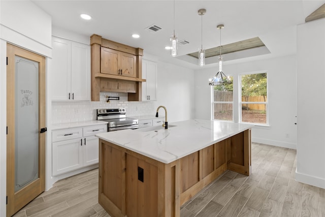 kitchen featuring electric stove, an island with sink, white cabinetry, and sink