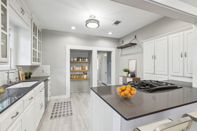 kitchen with a kitchen breakfast bar, gas cooktop, sink, and white cabinets