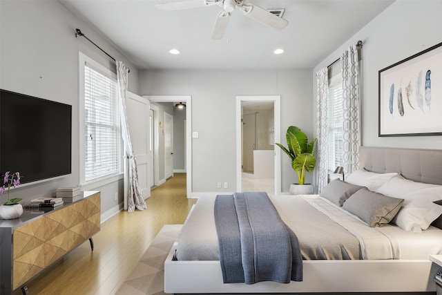 bedroom with ensuite bath, light hardwood / wood-style floors, multiple windows, and ceiling fan