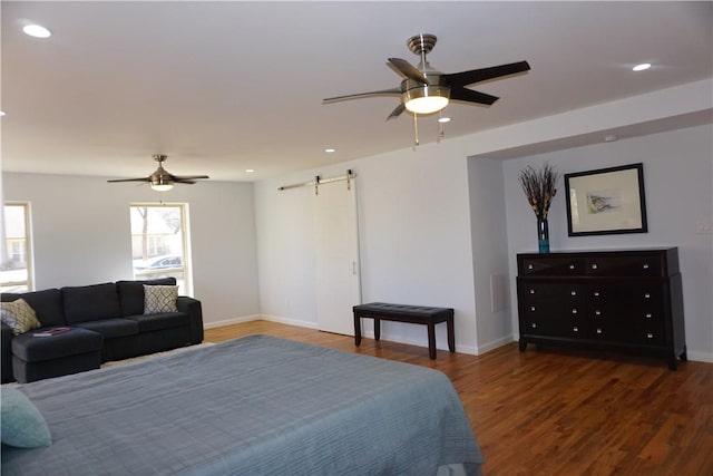 bedroom featuring a barn door, ceiling fan, and dark hardwood / wood-style floors