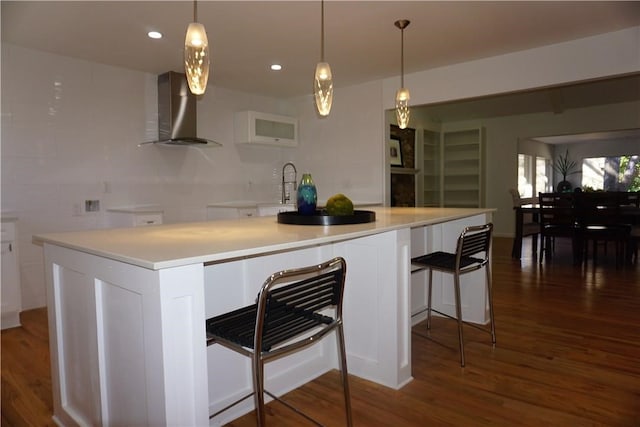 kitchen with wall chimney exhaust hood, wood-type flooring, and white cabinets