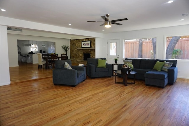 living room featuring a fireplace, hardwood / wood-style floors, and ceiling fan