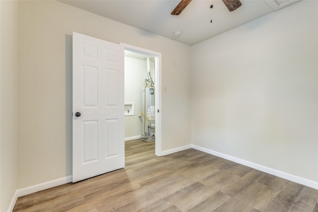 spare room featuring light wood-type flooring, ceiling fan, and water heater