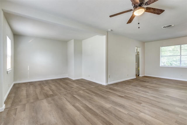 empty room with gas water heater, light hardwood / wood-style floors, and ceiling fan