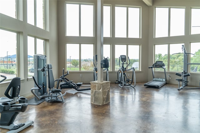 workout area featuring a towering ceiling and concrete floors