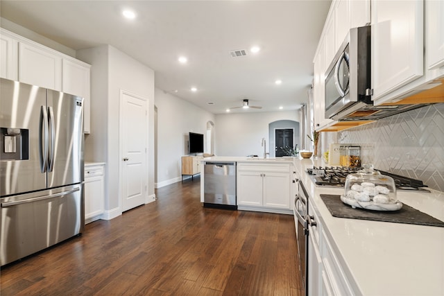 kitchen featuring white cabinets, appliances with stainless steel finishes, dark hardwood / wood-style floors, ceiling fan, and decorative backsplash