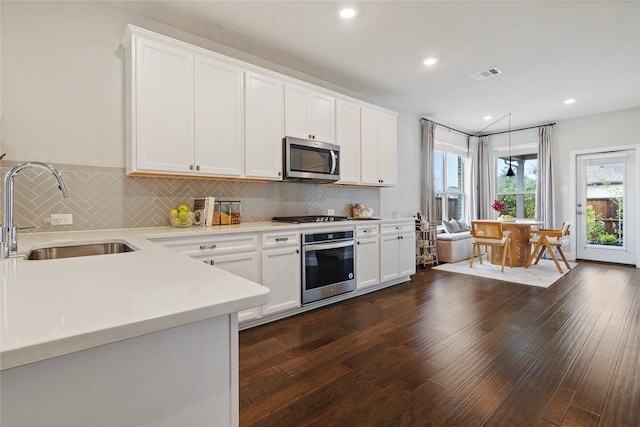 kitchen featuring white cabinets, appliances with stainless steel finishes, sink, dark hardwood / wood-style floors, and decorative backsplash