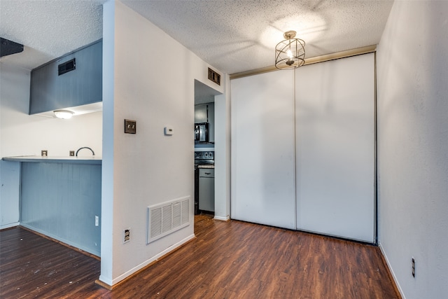 unfurnished room featuring dark wood-type flooring and a textured ceiling