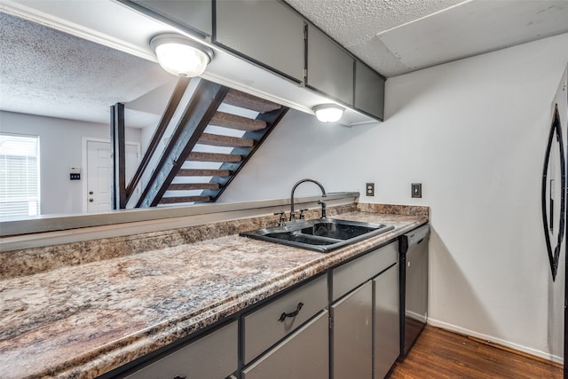 kitchen featuring a textured ceiling, stainless steel appliances, sink, dark wood-type flooring, and gray cabinetry