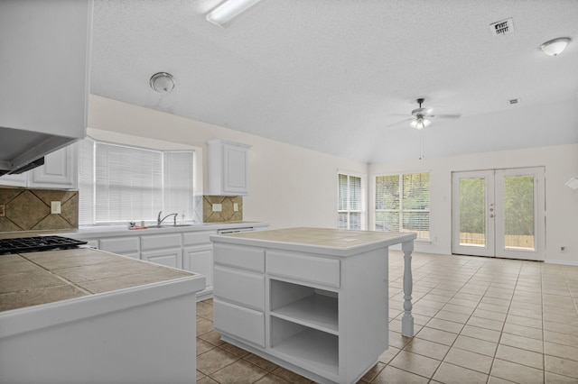 kitchen featuring white cabinets, a center island, ceiling fan, tasteful backsplash, and a breakfast bar