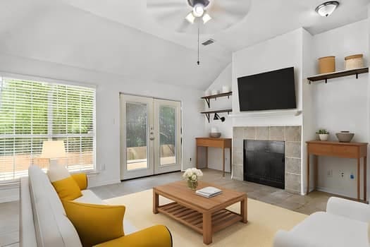 living room with a tiled fireplace, lofted ceiling, plenty of natural light, and ceiling fan