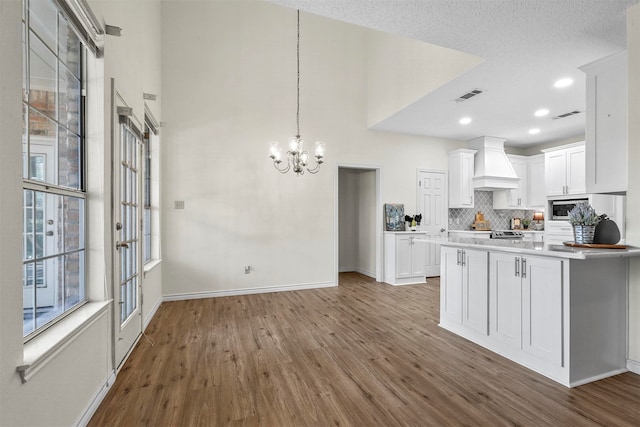 kitchen with white cabinetry, hardwood / wood-style floors, a textured ceiling, and custom exhaust hood