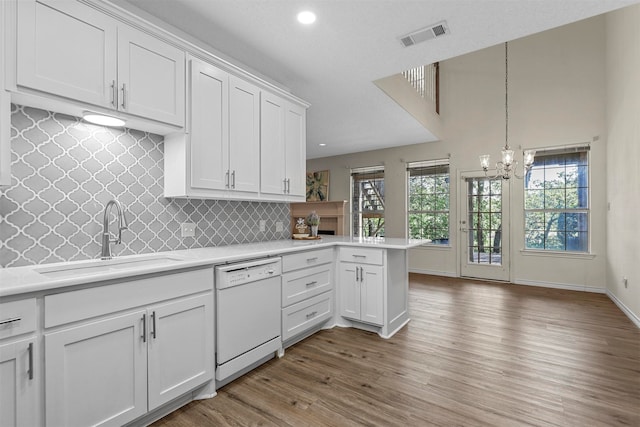 kitchen featuring white dishwasher, sink, decorative light fixtures, dark hardwood / wood-style flooring, and white cabinetry