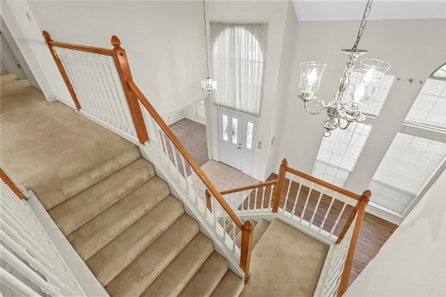 staircase featuring a high ceiling, a notable chandelier, and wood-type flooring