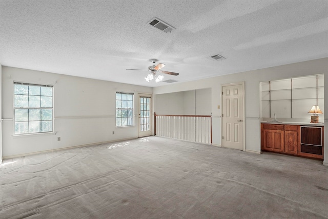 carpeted spare room with a textured ceiling and ceiling fan