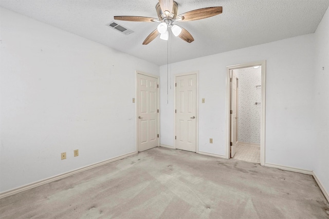 unfurnished bedroom with ensuite bath, ceiling fan, light colored carpet, and a textured ceiling