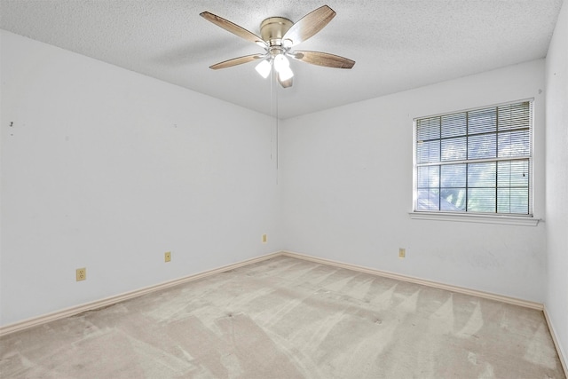 empty room featuring ceiling fan, light colored carpet, and a textured ceiling